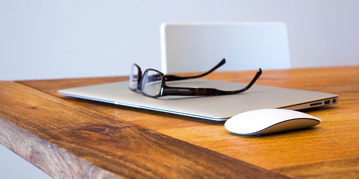 A black eyeglass on top of a laptop